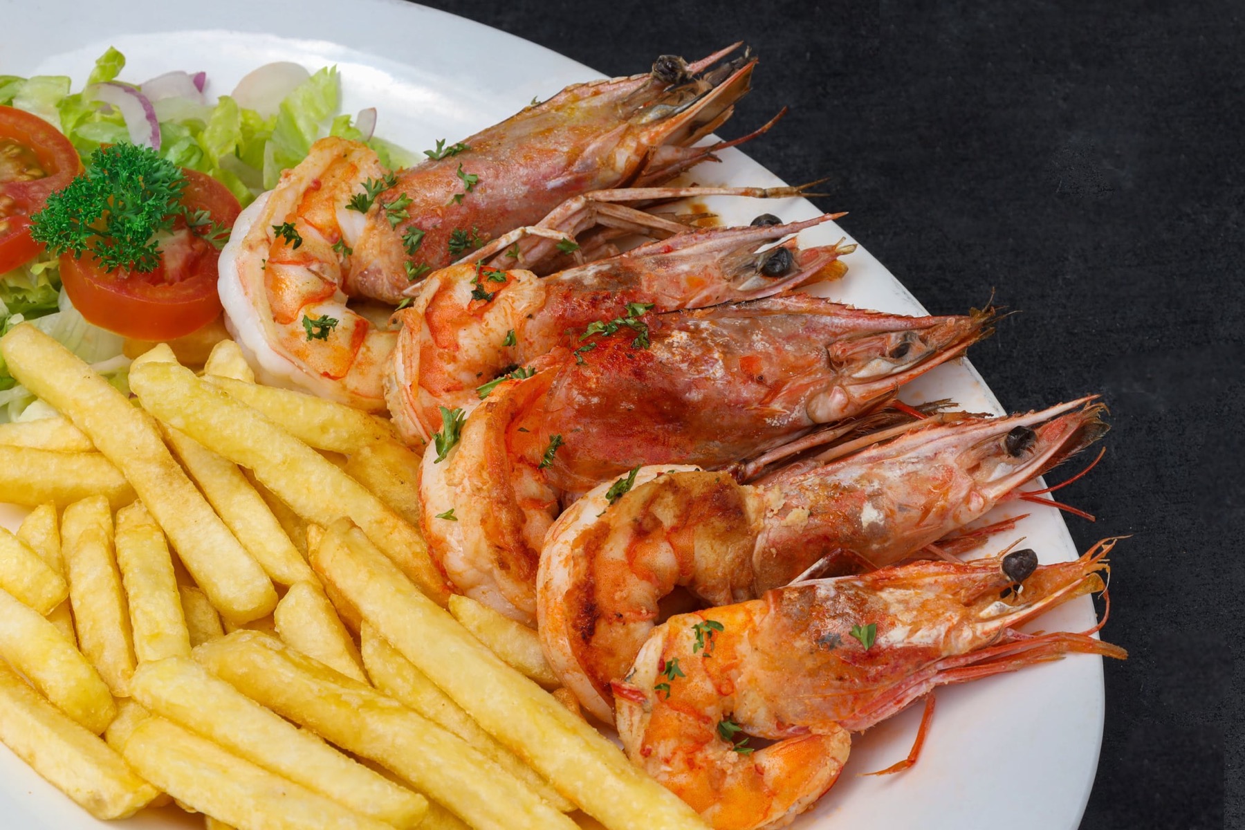 Camarones servidos con papas y ensalada